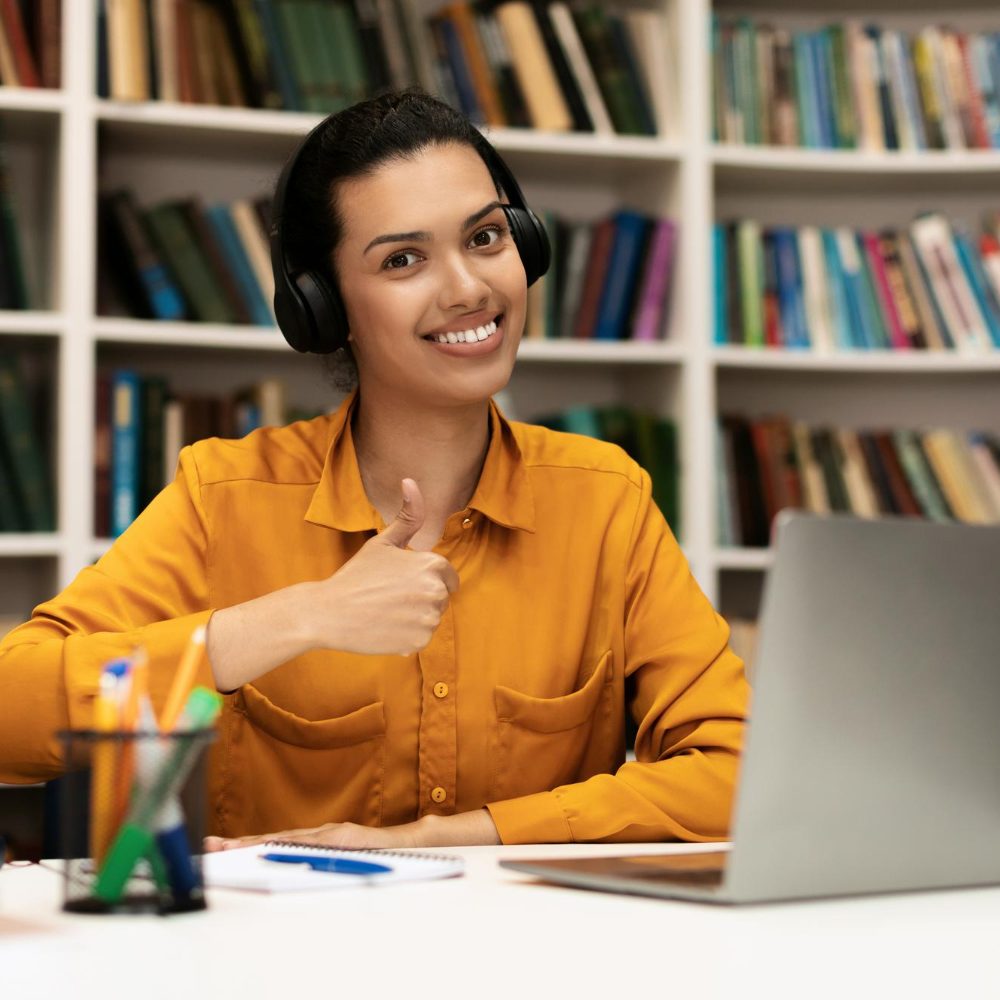 me-gusta-aprendizaje-distancia-feliz-estudiante-gesticulando-pulgar-arriba-sentada-escritorio-computadora-portatil